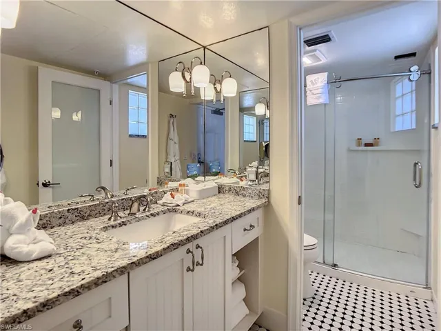 Bathroom featuring vanity, toilet, tile patterned floors, and an enclosed shower