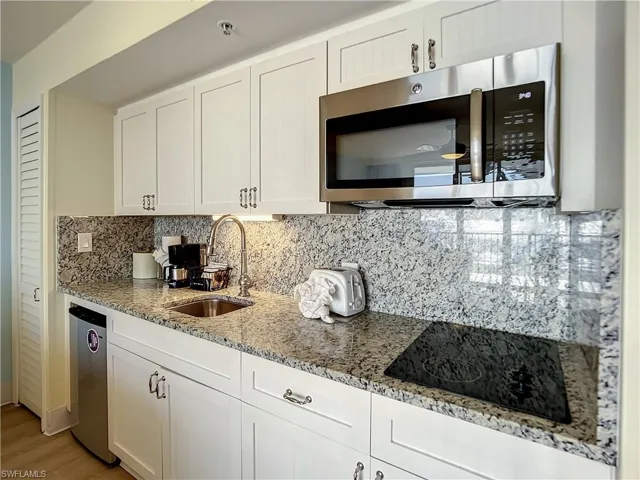 Kitchen with white cabinetry, tasteful backsplash, light wood-type flooring, sink, and appliances with stainless steel finishes