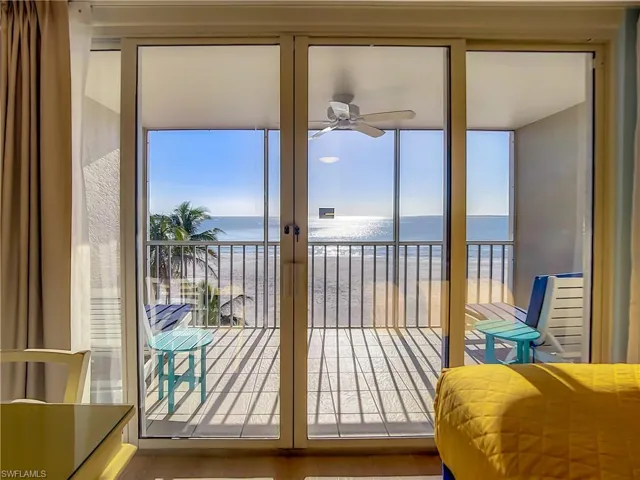 Doorway to outside featuring a view of the beach, a water view, hardwood / wood-style flooring, and ceiling fan