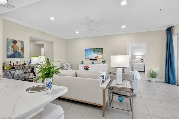 Living area with crown molding, a ceiling fan, light tile patterned floors, and recessed lighting