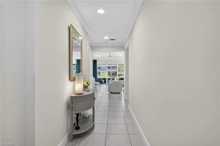 Hallway with crown molding, light tile patterned flooring, and recessed lighting