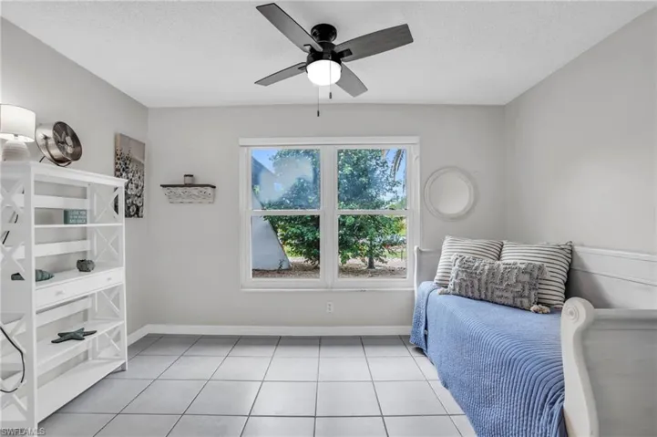 Bedroom with ceiling fan, a textured ceiling, and light tile patterned floors