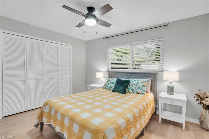 Bedroom with ceiling fan, a textured ceiling, light hardwood / wood-style floors, and a closet