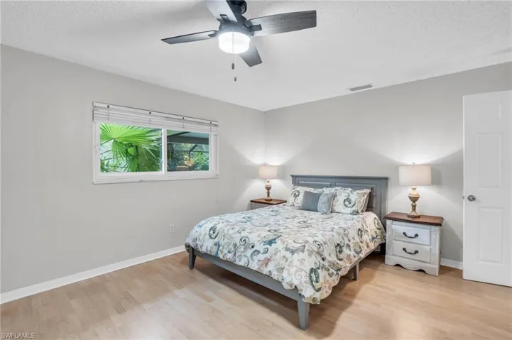 Bedroom with ceiling fan, a textured ceiling, and light hardwood / wood-style floors