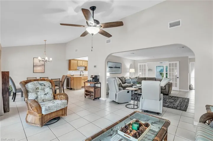 Tiled living room featuring sink, high vaulted ceiling, and ceiling fan with notable chandelier