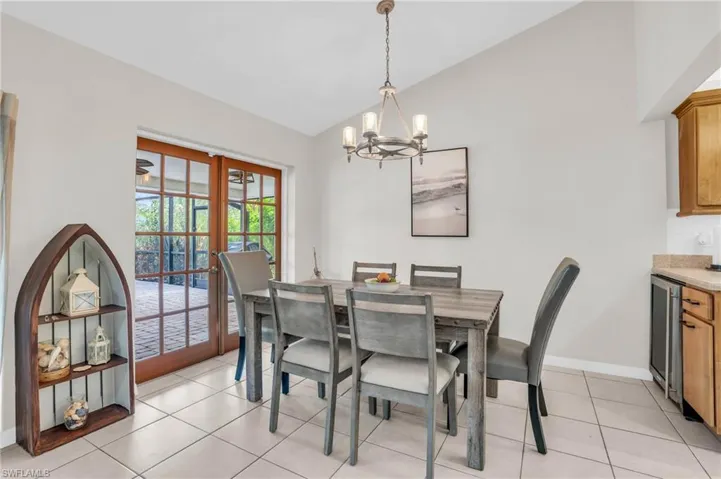 Tiled dining space with high vaulted ceiling, an inviting chandelier, and french doors