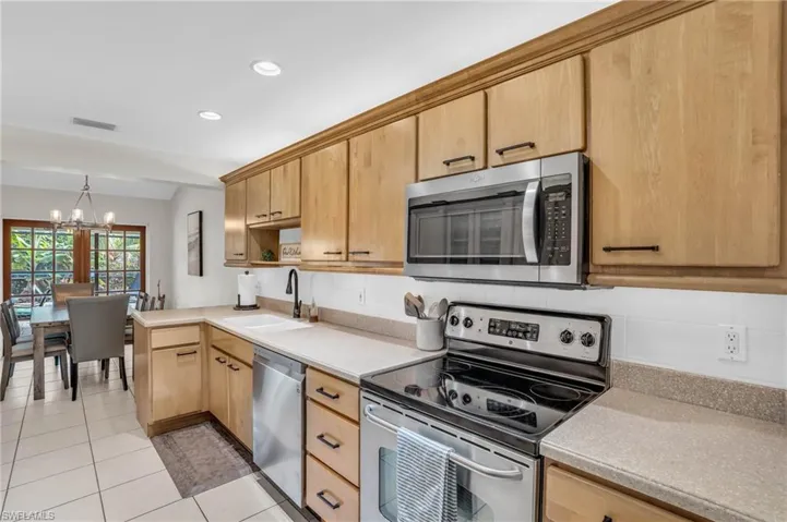 Kitchen featuring a chandelier, light tile patterned flooring, backsplash, stainless steel appliances, and sink