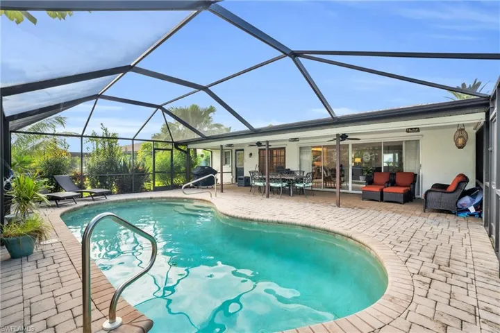 View of swimming pool featuring ceiling fan, a patio, glass enclosure, and an outdoor living space