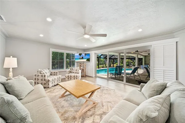 Living area featuring wood finished floors, ornamental molding, a sunroom, ceiling fan, and recessed lighting