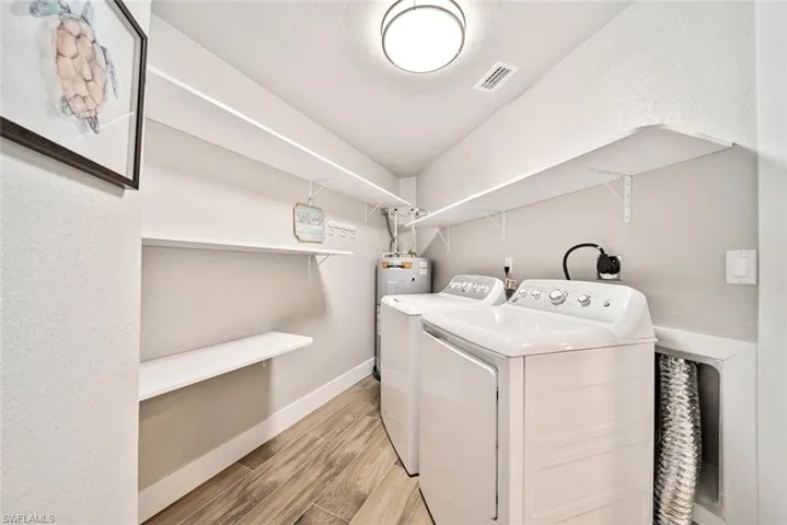 Laundry area featuring wood finish floors, washer and clothes dryer, and electric water heater