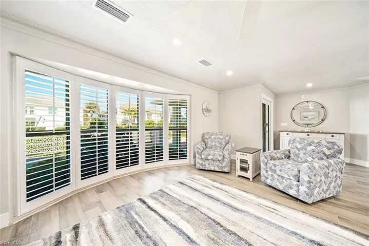 Sitting room with ornamental molding, light wood-style flooring, and recessed lighting