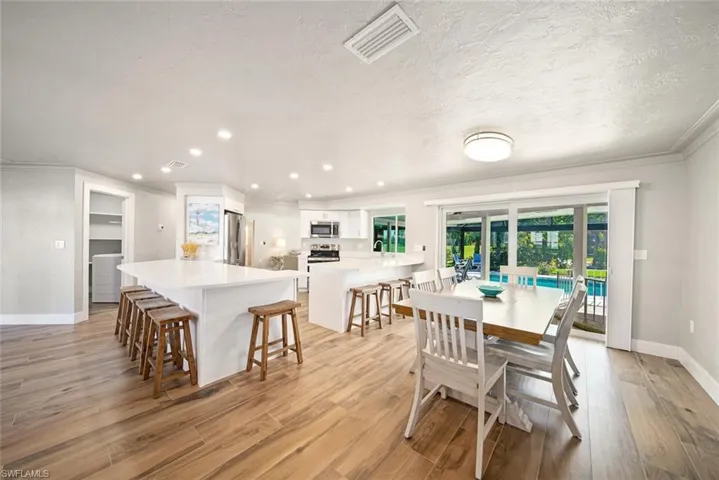 Dining area featuring light wood-style flooring, crown molding, a textured ceiling, and recessed lighting