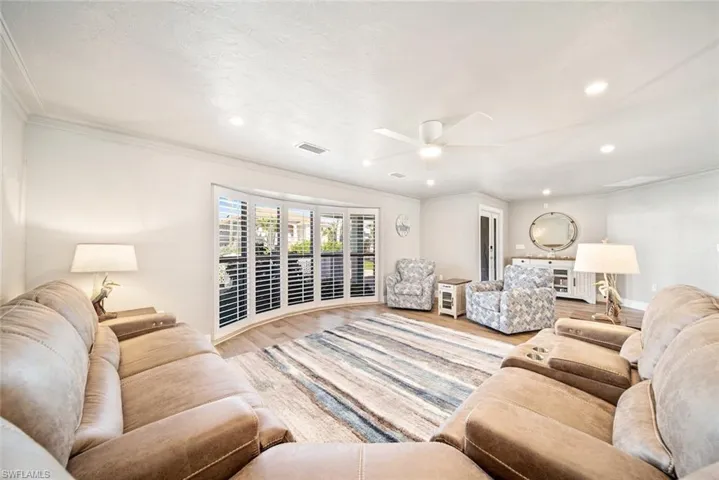 Living room featuring wood finished floors, ornamental molding, ceiling fan, and recessed lighting