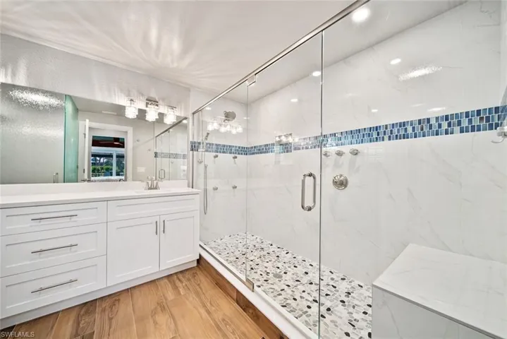 Bathroom with a marble finish shower, vanity, and light wood-style flooring