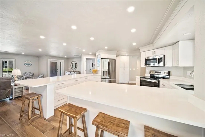 Kitchen featuring a peninsula, a breakfast bar, appliances with stainless steel finishes, white cabinetry, and open floor plan