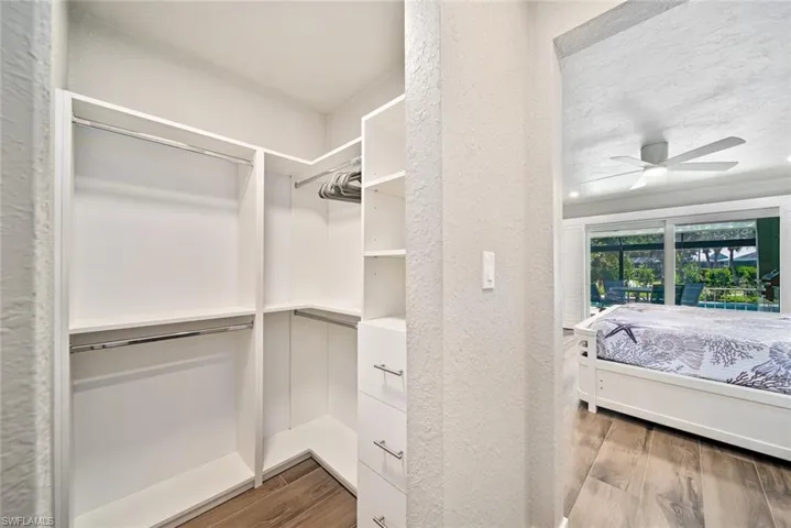 Spacious closet with light wood finished floors and a ceiling fan