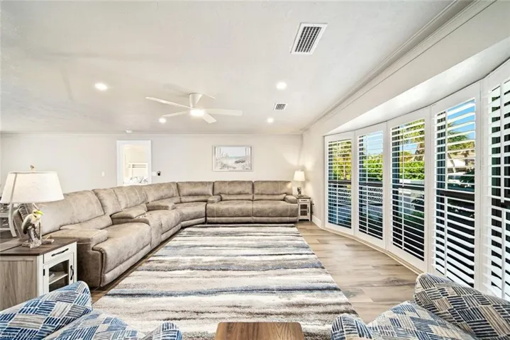 Living area with crown molding, light wood-style floors, ceiling fan, and recessed lighting