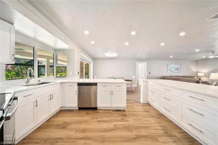 Kitchen with open floor plan, white cabinets, a peninsula, recessed lighting, and appliances with stainless steel finishes