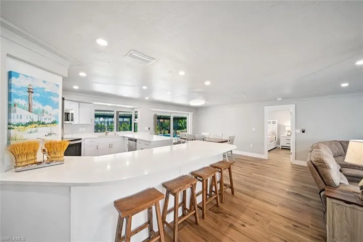 Kitchen featuring a peninsula, light wood-style floors, a kitchen breakfast bar, white cabinetry, and crown molding