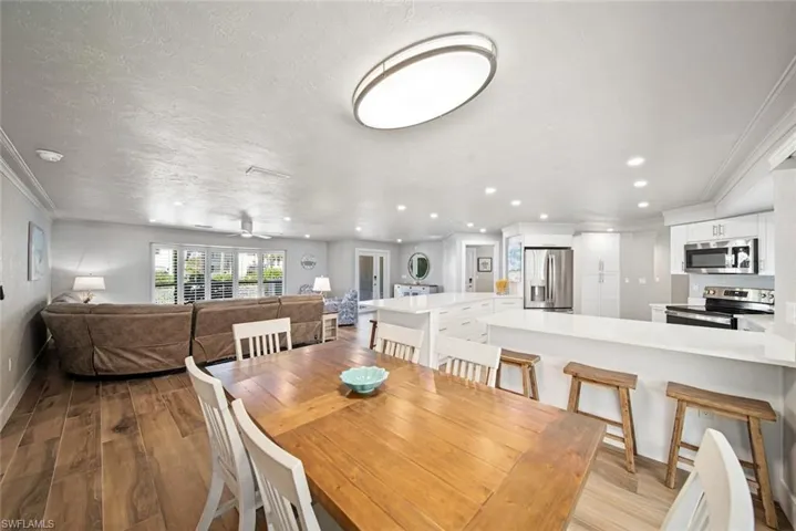 Dining area featuring ornamental molding, light wood-type flooring, recessed lighting, a textured ceiling, and a ceiling fan