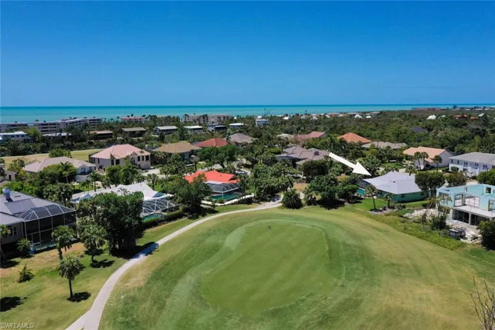 Aerial view of residential area featuring a local golf course and a large body of water