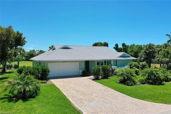 Single story home with a front lawn, an attached garage, and decorative driveway