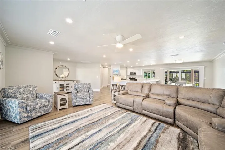 Living area featuring recessed lighting, wood finished floors, a ceiling fan, and ornamental molding