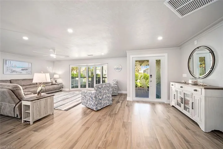 Living room with light wood-style floors, recessed lighting, ceiling fan, a textured ceiling, and ornamental molding