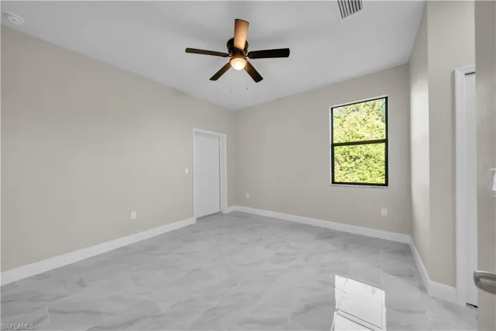 Rear view of house featuring ceiling fan, stucco siding, and a lawn