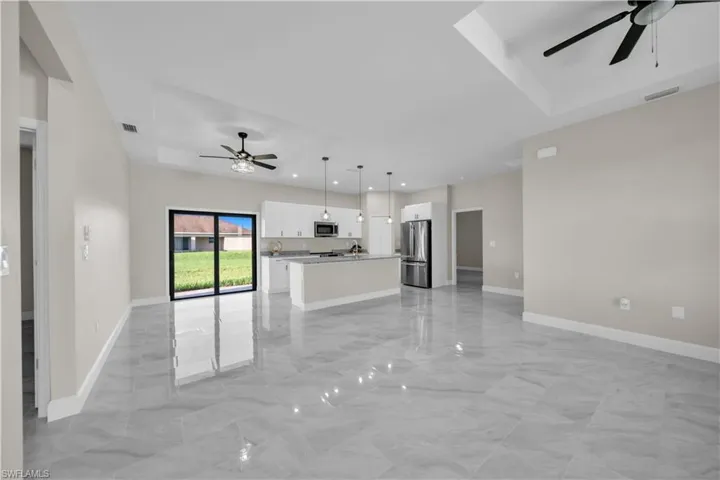 Kitchen with ceiling fan, stainless steel appliances, light marble finish flooring, hanging light fixtures, and white cabinetry