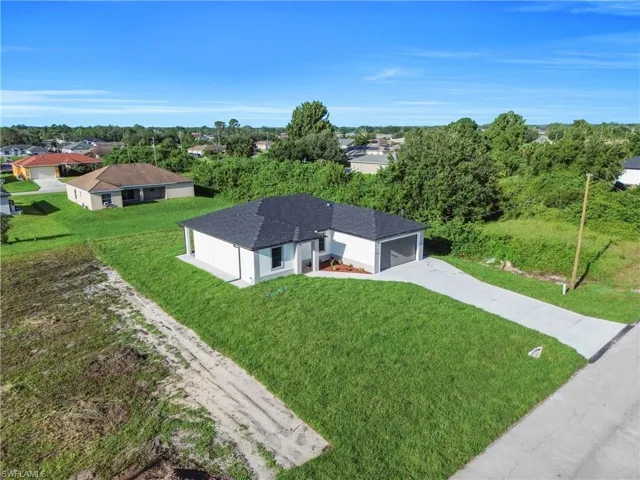 Prairie-style home with concrete driveway, an attached garage, a lawn, and stucco siding