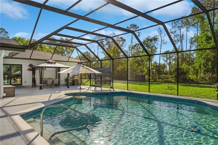 View of swimming pool with a lanai, a patio area, and a lawn