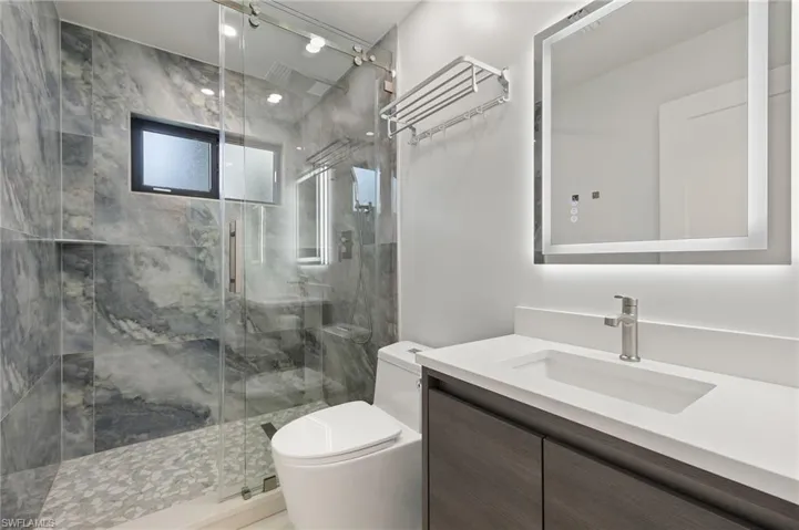 Guest Bathroom 2featuring vanity, toilet, and a shower with door