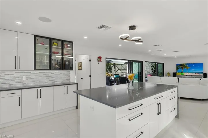 Kitchen with white cabinets, decorative backsplash, a kitchen island, and hanging light fixtures