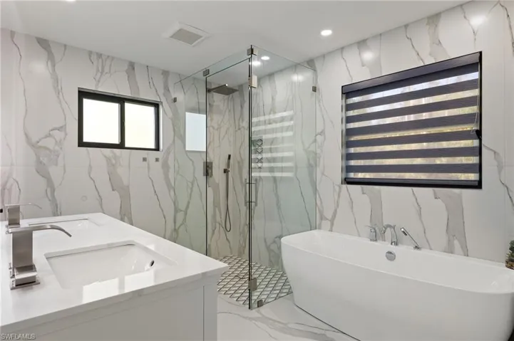 Owner's suit Bathroom with vanity, tile walls, and shower with separate bathtub