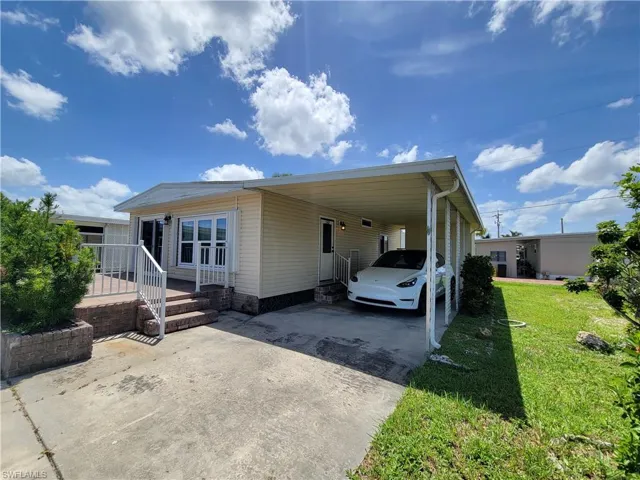 View of front of property with an attached carport, driveway, and a front yard