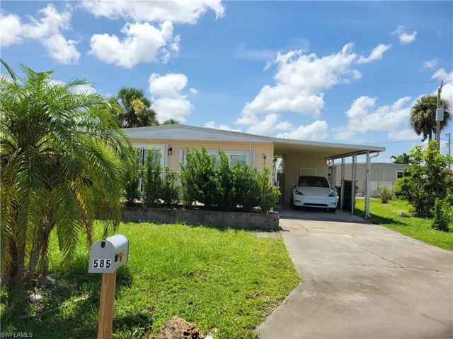 View of front of home with driveway, a carport, and a front yard