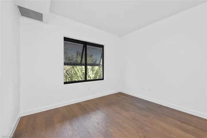 Unfurnished room with baseboards and dark wood-style floors