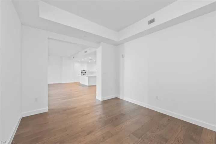 Unfurnished room featuring dark wood-type flooring, a raised ceiling, and recessed lighting