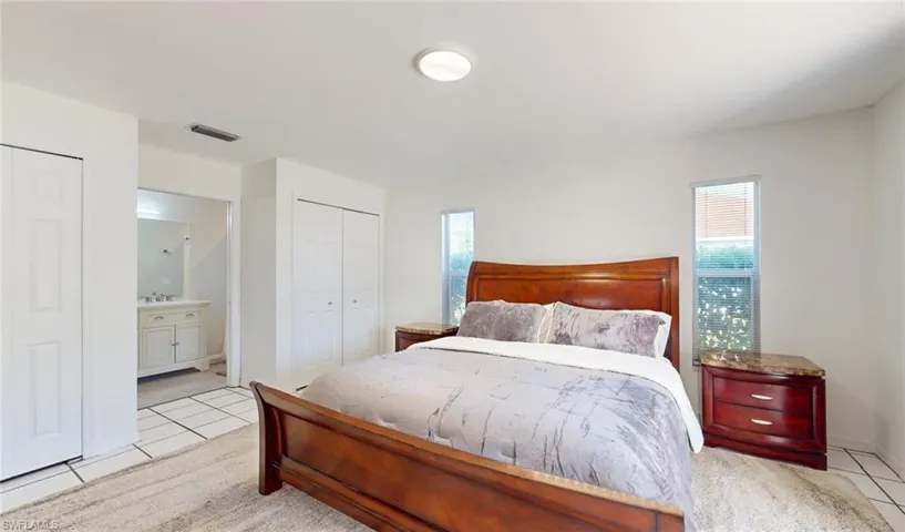 Bedroom featuring ensuite bathroom, multiple windows