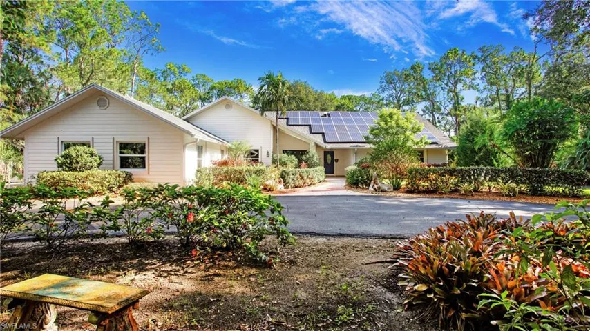 Single story home with roof mounted solar panels and driveway