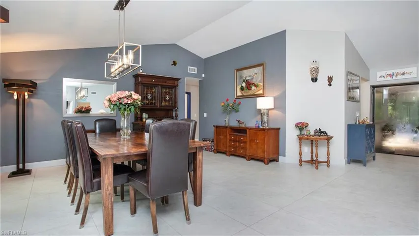 Dining area featuring vaulted ceiling, light tile patterned floors, and a chandelier