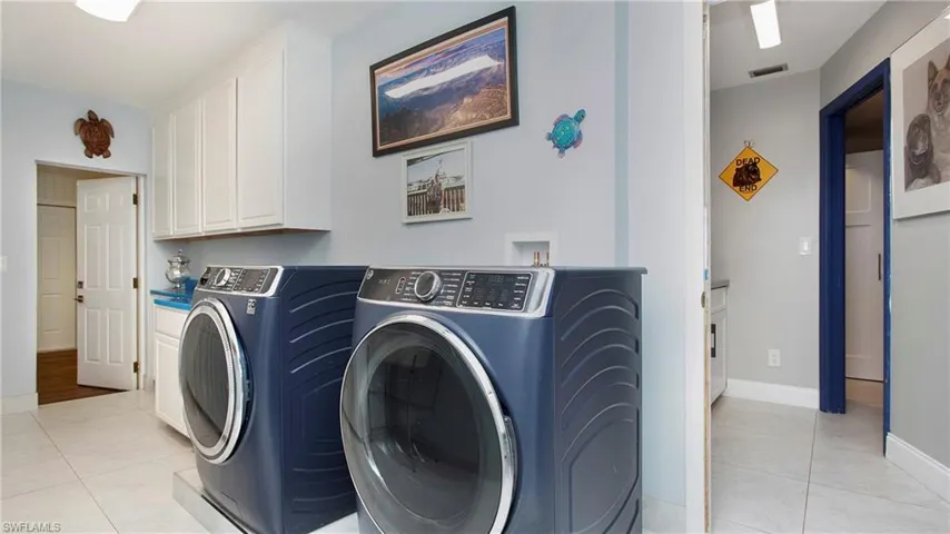 Laundry area with washing machine and clothes dryer, cabinet space, and light tile patterned floors