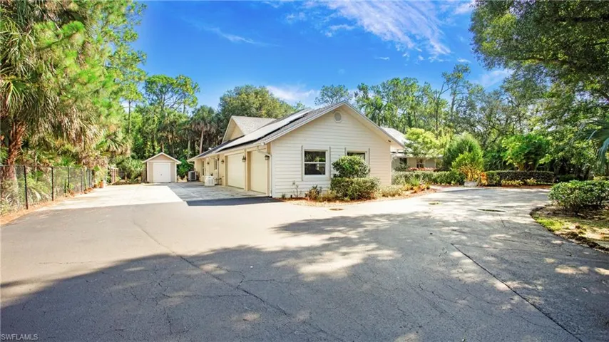 View of home's exterior with driveway, a garage, roof mounted solar panels, and a storage unit