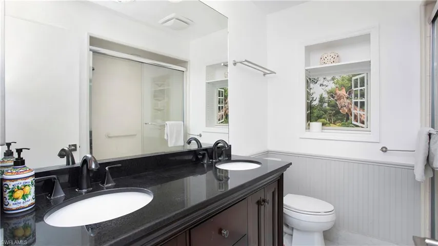 Full bathroom with a wainscoted wall, double vanity, and a shower with shower door