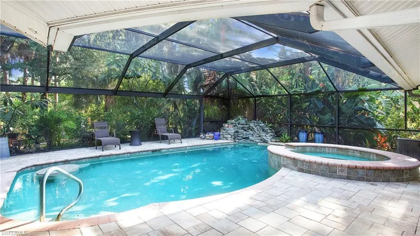 View of swimming pool featuring a pool with connected hot tub, a lanai, and a patio area