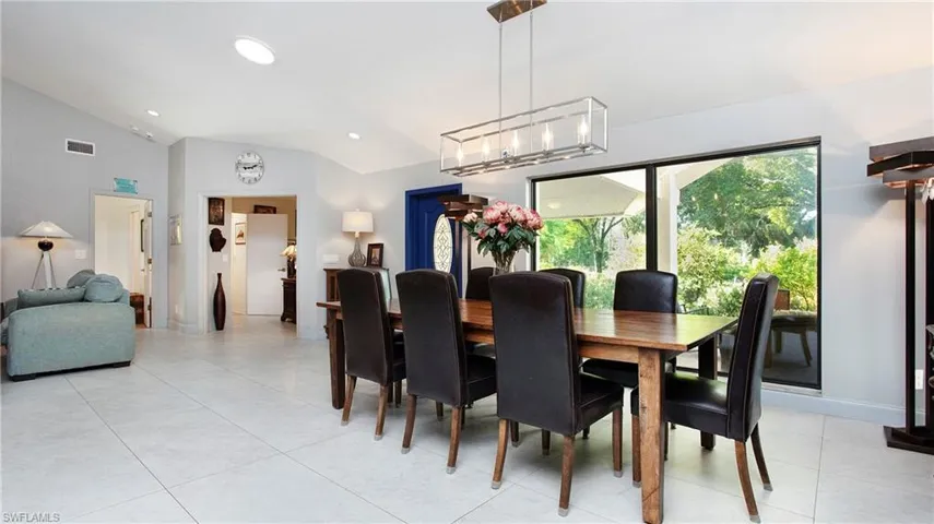Dining area with lofted ceiling, light tile patterned floors, recessed lighting, and a chandelier