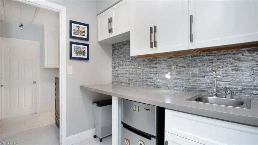 Kitchen featuring light tile patterned floors, white cabinets, refrigerator, and decorative backsplash
