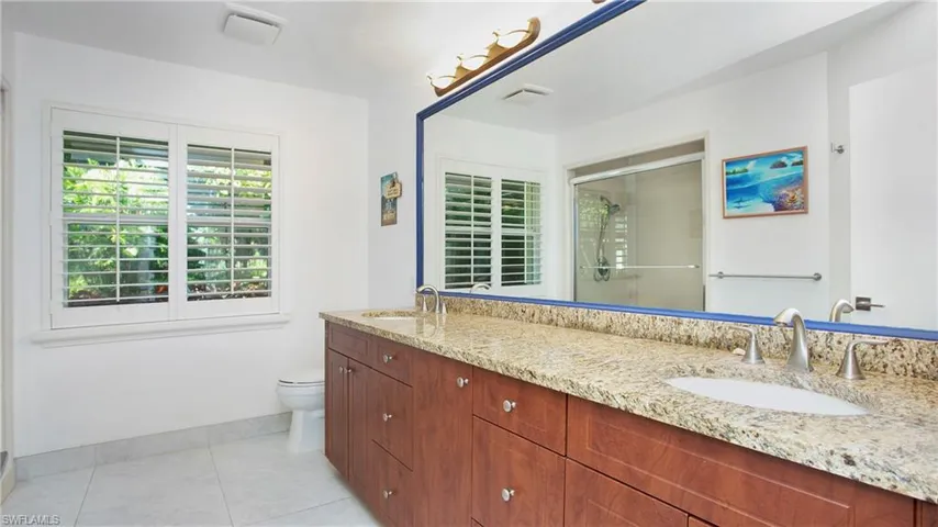 Full bath featuring a stall shower, double vanity, and tile patterned floors