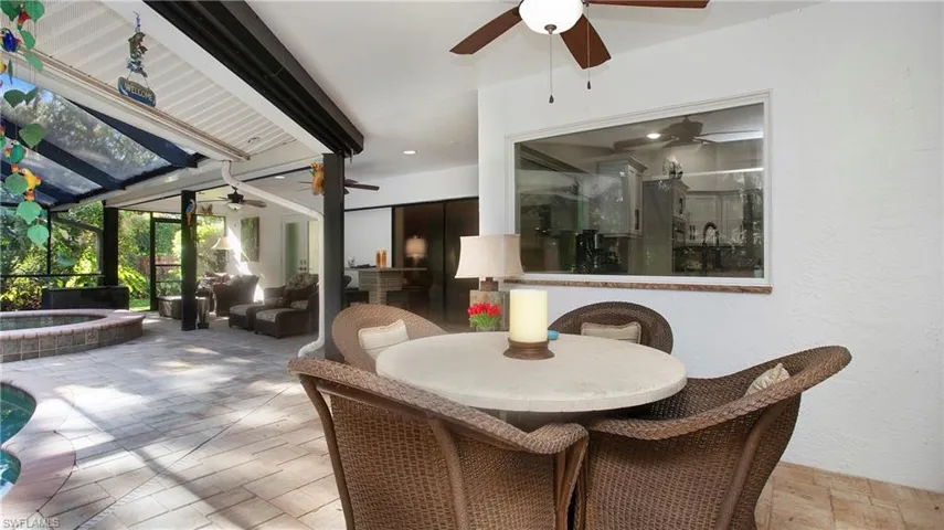 View of patio featuring ceiling fan, an in-ground hot tub, outdoor dining space, a lanai, and an outdoor pool